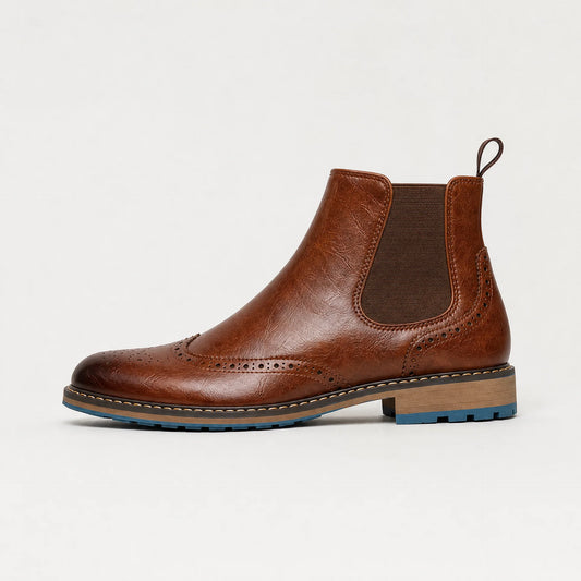 A brown leather Chelsea boot with brogue detailing, a brown elastic side panel, and a stacked wood-look heel with a blue outsole, shown against a plain white background.