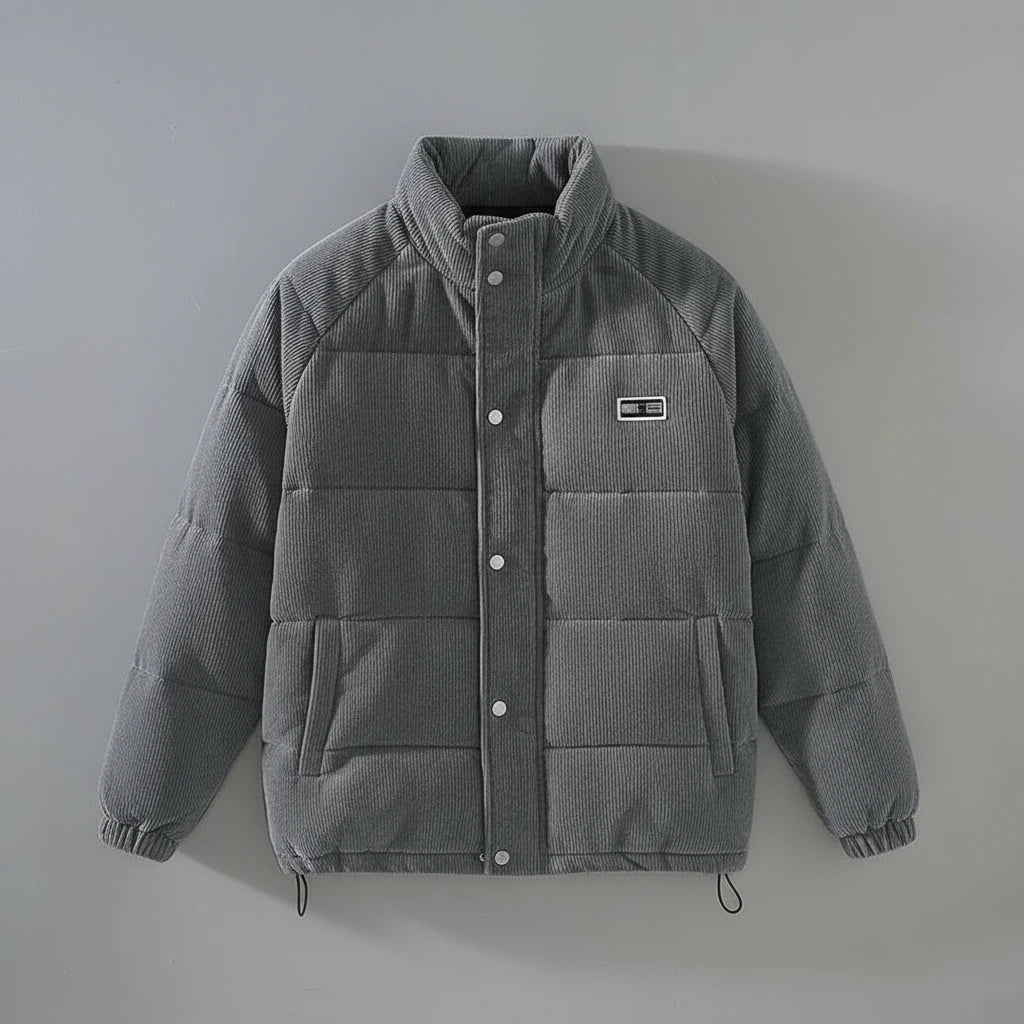 A gray quilted puffer jacket with a stand-up collar, snap-button front, elastic cuffs, and a small rectangular chest patch, shown against a plain light gray background.